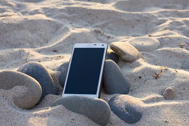 Smartphone auf Steinen im Sand an der Nordsee